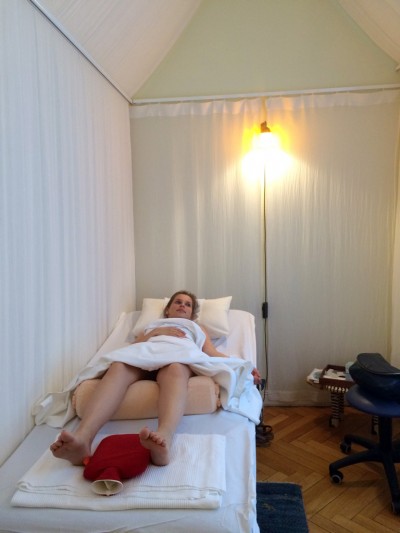 Frau im beleuchteten Behandlungszelt mit roter Wärmflasche